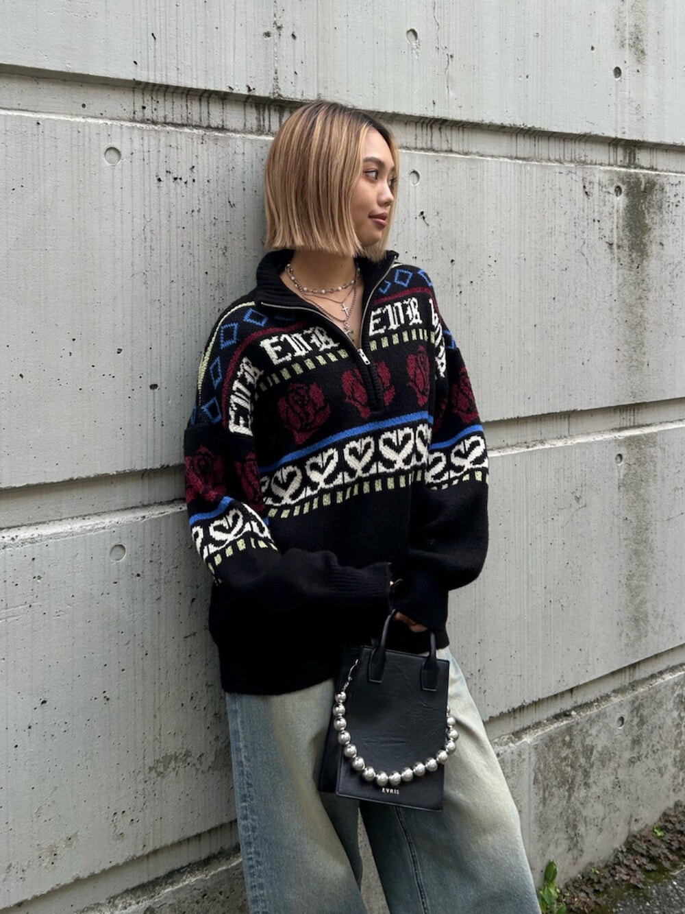 ブラック系のショルダーバッグ、ブラック系のニット/セーター、ブルー系のデニムパンツを着用したレディースの秋コーディネートの4枚目の写真