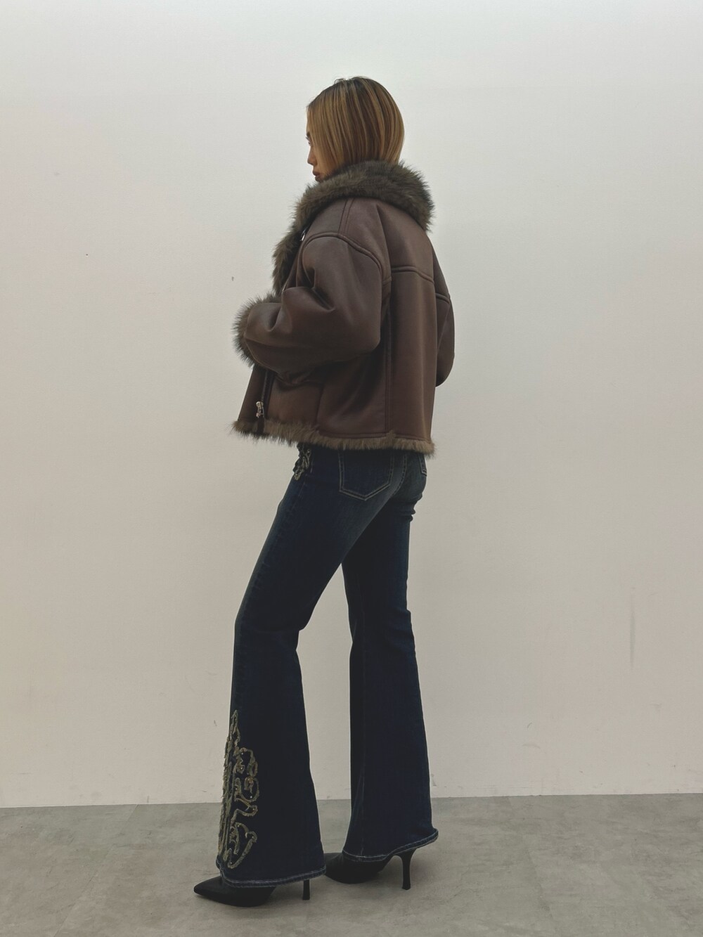 ブラウン系のブルゾン、ホワイト系のニット/セーター、ブルー系のデニムパンツを着用したレディースの秋コーディネートの2枚目の写真