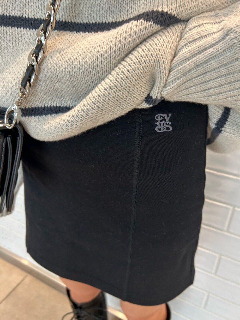 ブラック系のショルダーバッグ、ブラック系のスカート、ブラック系のブーツを着用したレディースの夏コーディネートの4枚目の写真