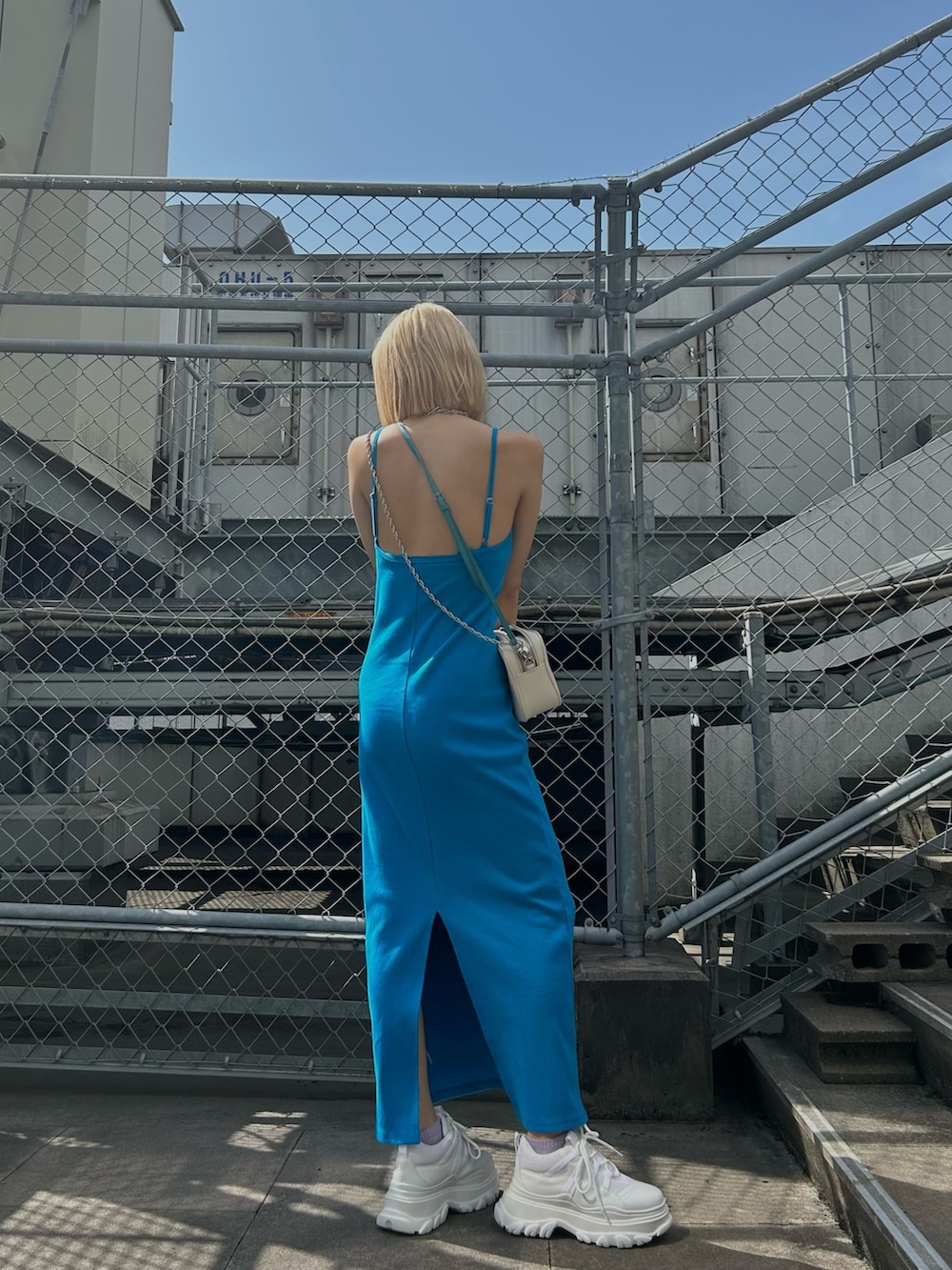 ブルー系のワンピース、ホワイト系のショルダーバッグ、ホワイト系のスニーカーを着用したレディースの春コーディネートの3枚目の写真