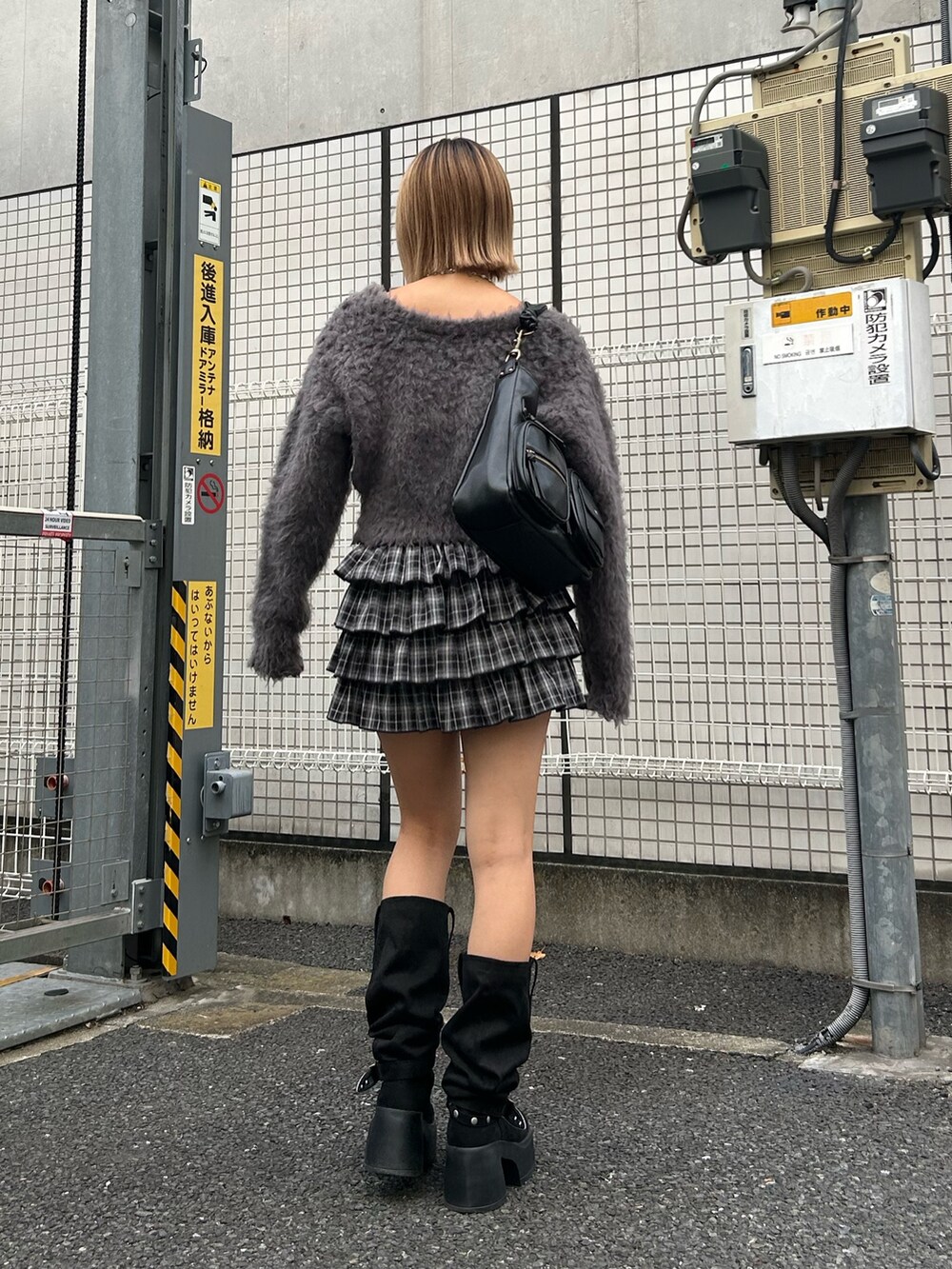 グレー系のニット/セーター、ブラック系のスカート、ブラック系のハンドバッグを着用したレディースの秋コーディネートの2枚目の写真