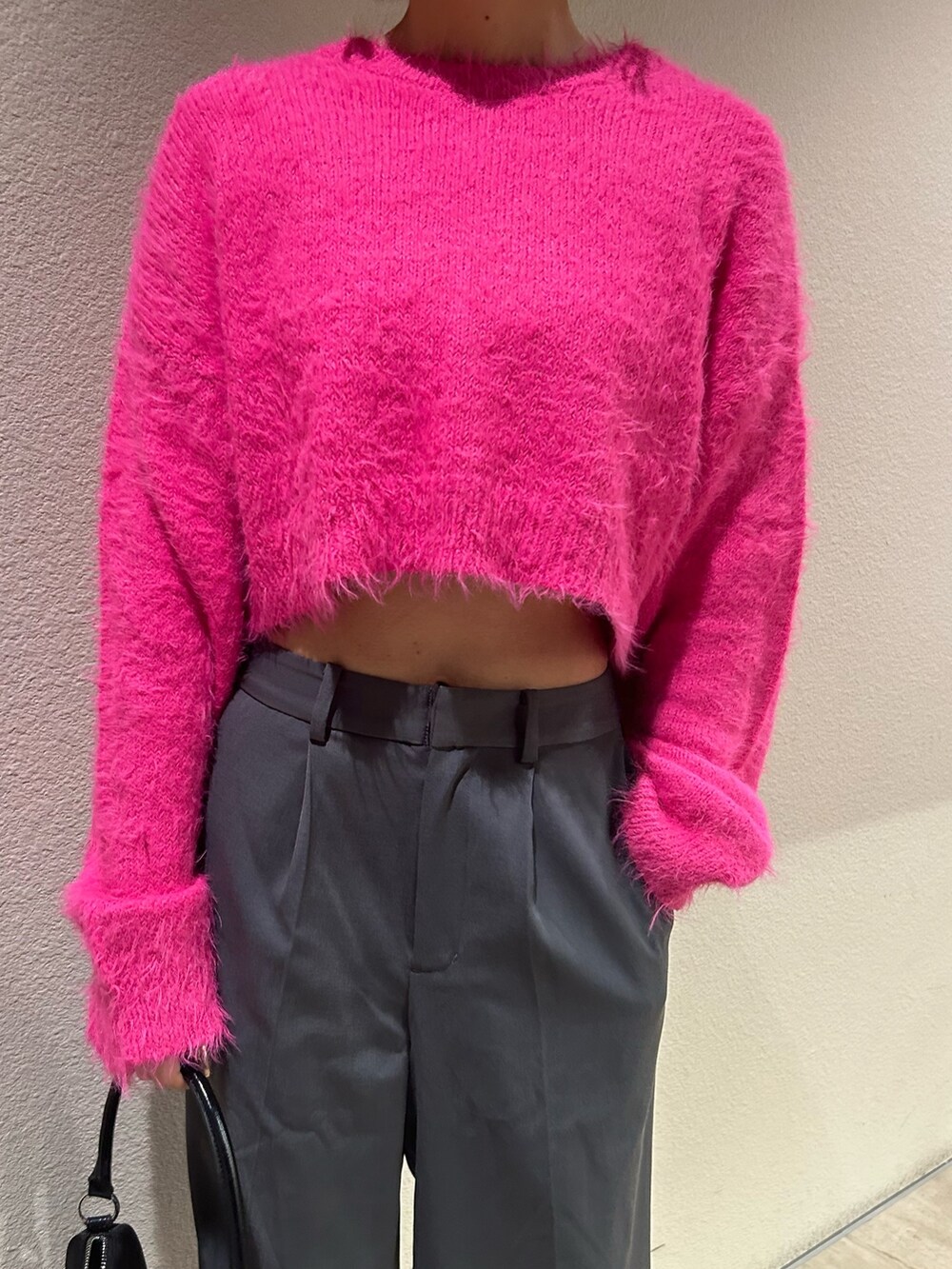 グレー系のその他パンツ、ピンク系のニット/セーター、ブラック系のハンドバッグを着用したレディースの冬コーディネートの2枚目の写真