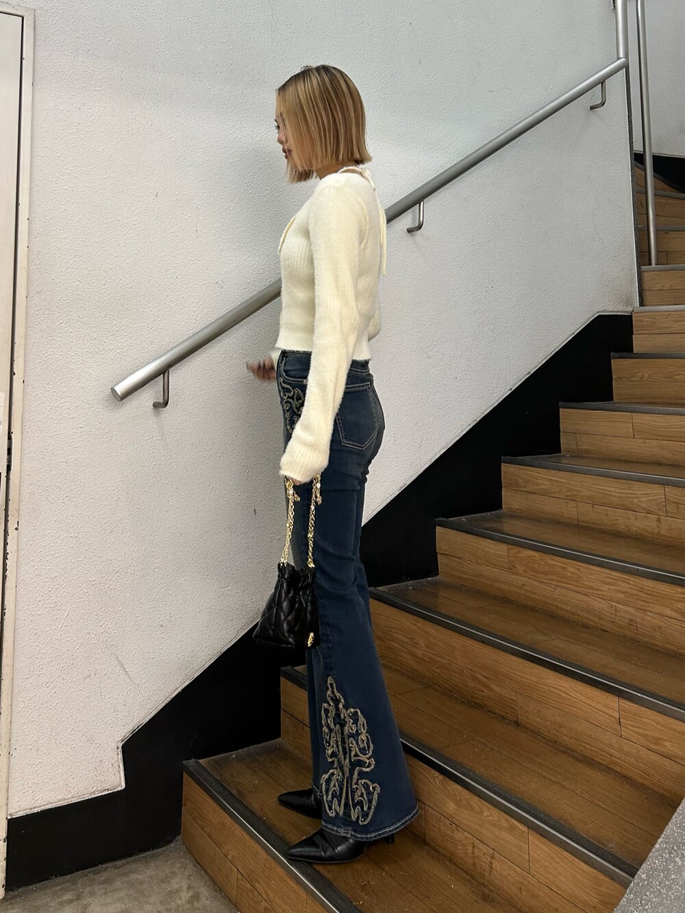 ホワイト系のニット/セーター、ブラック系のショルダーバッグ、ブルー系のデニムパンツを着用したレディースの秋コーディネートの2枚目の写真