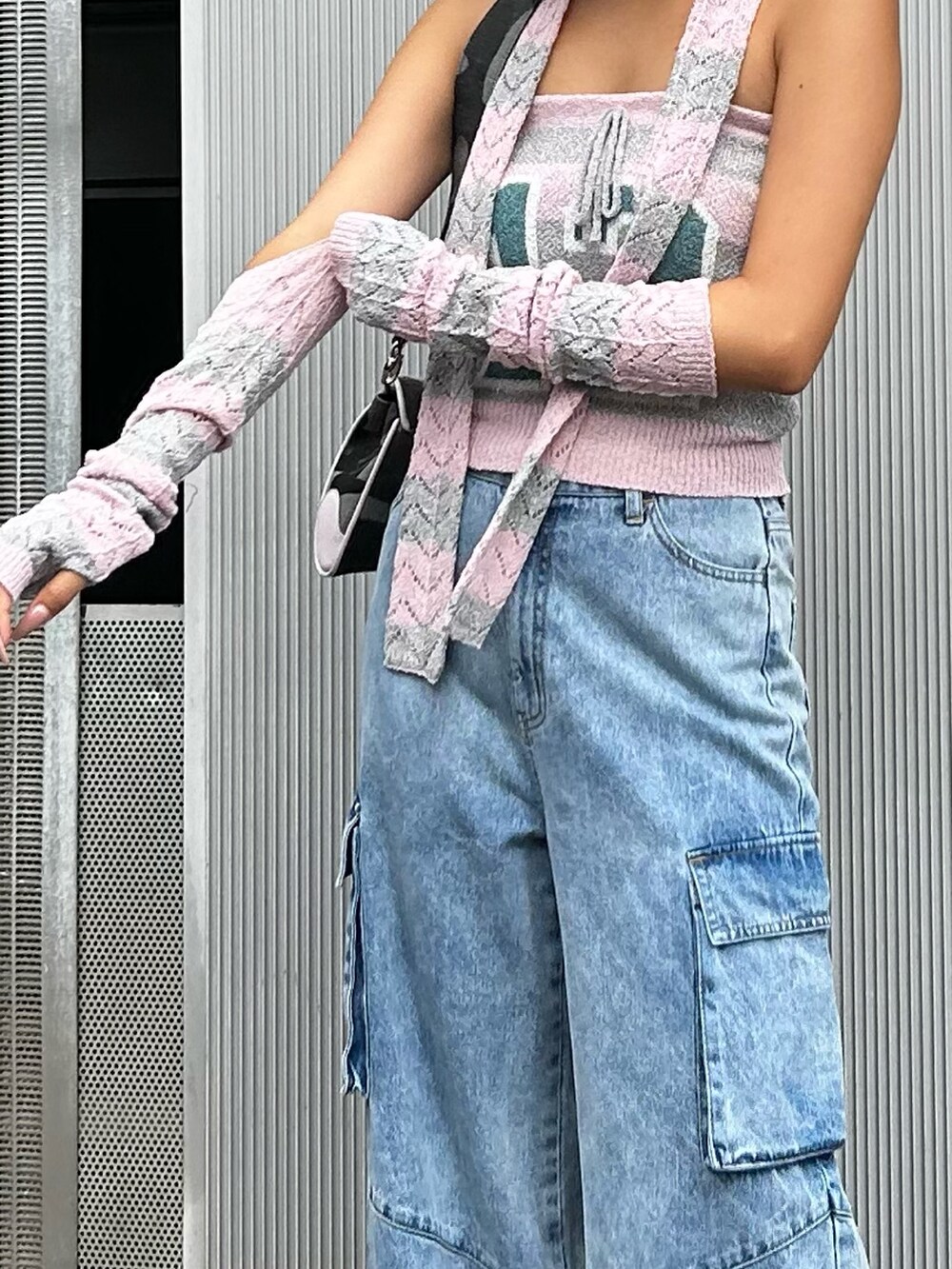 ピンク系のニット/セーター、ブルー系のデニムパンツ、ブラック系のショルダーバッグを着用したレディースの秋コーディネートの4枚目の写真