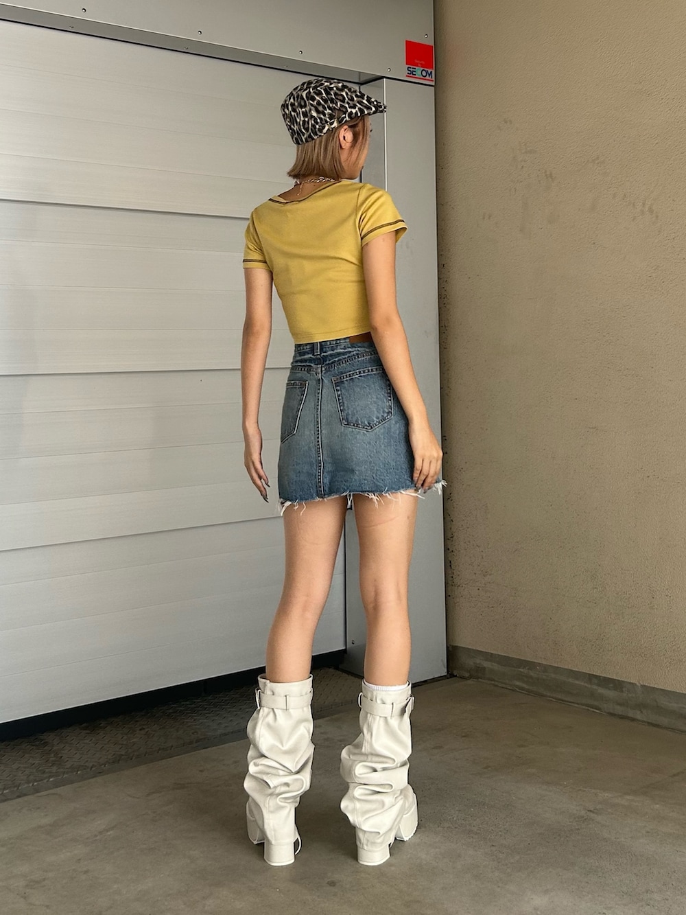 ブルー系のデニムスカート、イエロー系のTシャツ/カットソー、ホワイト系のブーツを着用したレディースの夏コーディネートの2枚目の写真