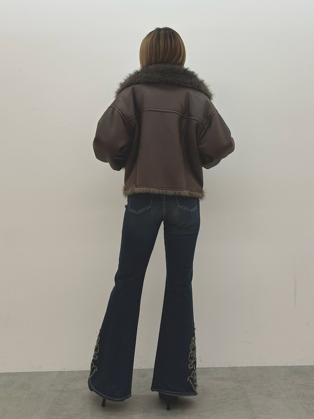 ブラウン系のブルゾン、ホワイト系のニット/セーター、ブルー系のデニムパンツを着用したレディースの秋コーディネートの3枚目の写真