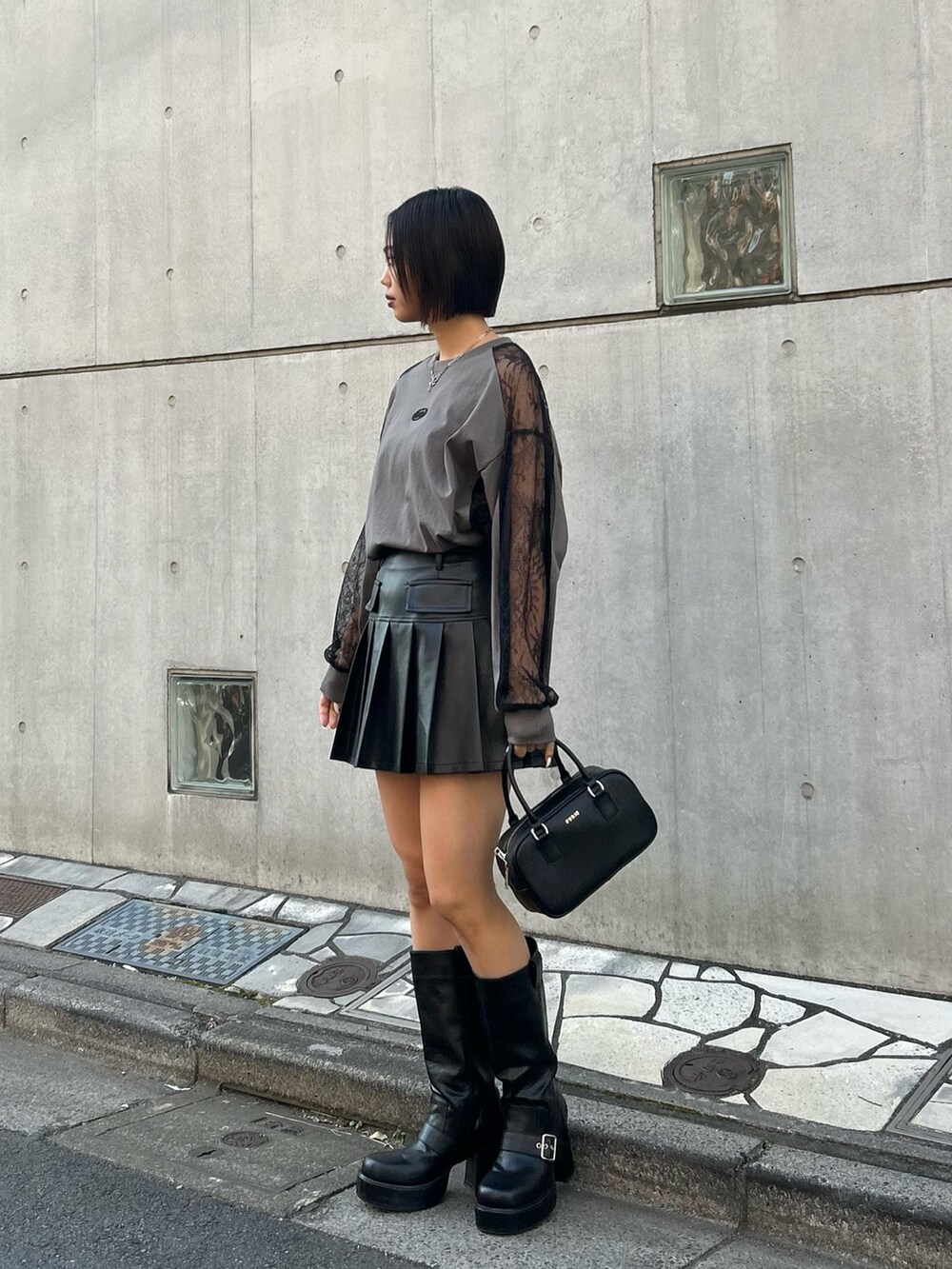 グレー系のTシャツ/カットソー、ブラック系のスカート、ブラック系のボストンバッグを着用したレディースの冬コーディネートの2枚目の写真