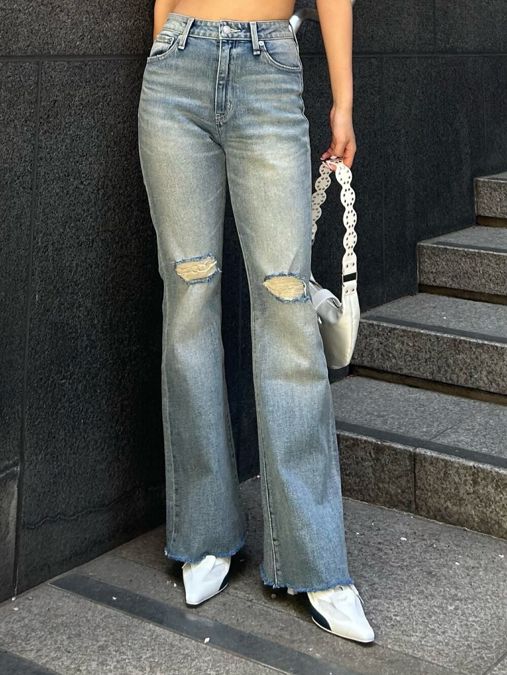ブルー系のデニムパンツ、ホワイト系のパンプス、ホワイト系のショルダーバッグを着用したレディースの春コーディネートの3枚目の写真