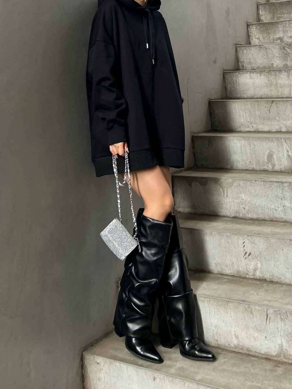 ブラック系のパーカー、ブラック系のブーツ、シルバー系のショルダーバッグを着用したレディースの冬コーディネートの3枚目の写真