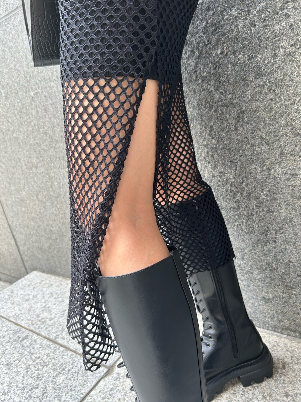 ブラック系のワンピース、ブラック系のハンドバッグ、ブラック系のブーツを着用したレディースの夏コーディネートの2枚目の写真