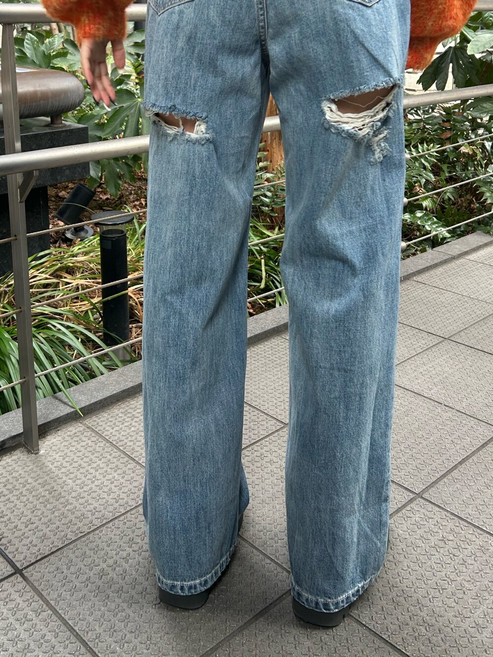 ブルー系のデニムパンツ、オレンジ系のニット/セーター、ブラック系のブーツを着用したレディースの冬コーディネートの4枚目の写真