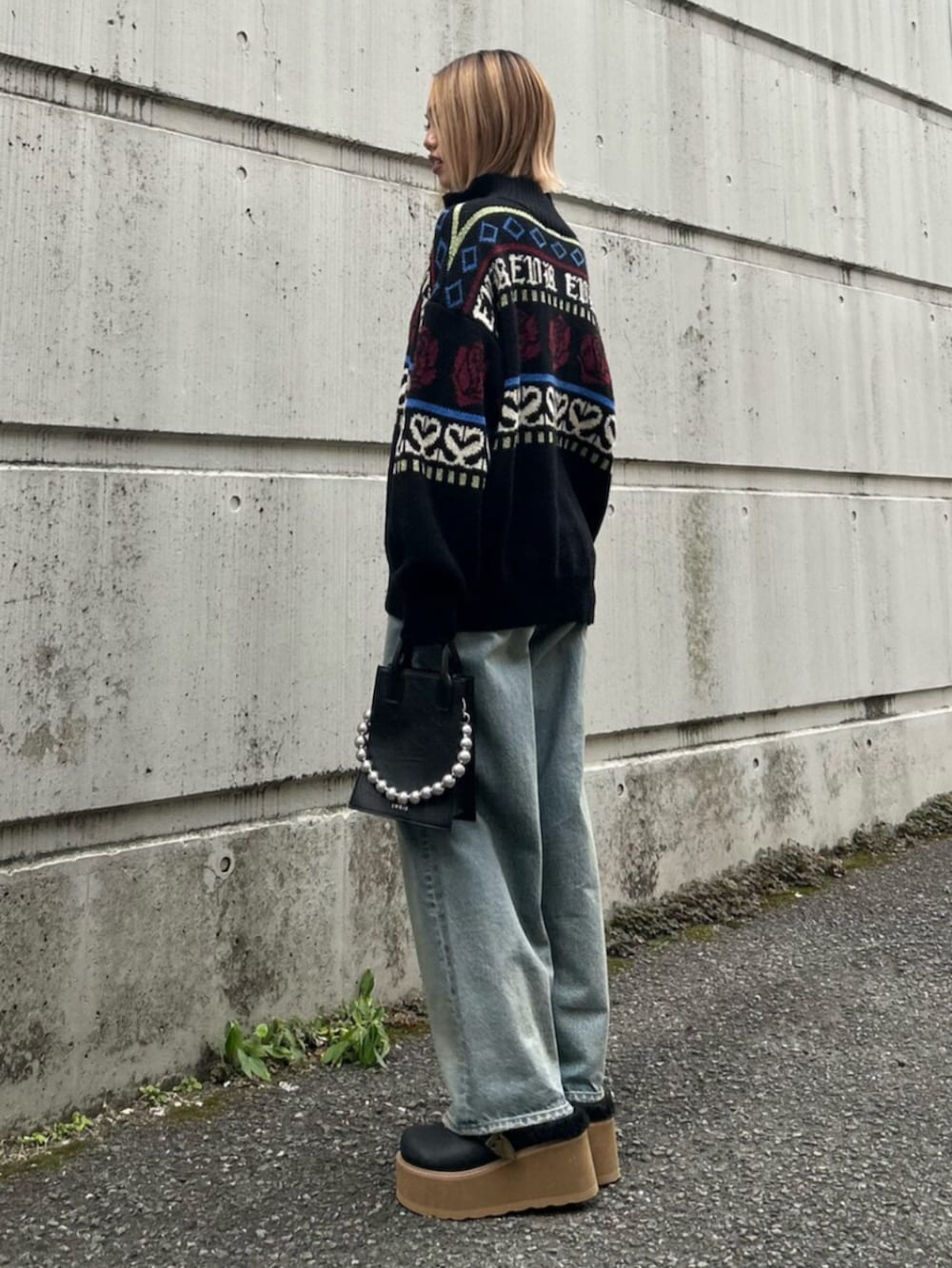 ブラック系のショルダーバッグ、ブラック系のニット/セーター、ブルー系のデニムパンツを着用したレディースの秋コーディネートの2枚目の写真