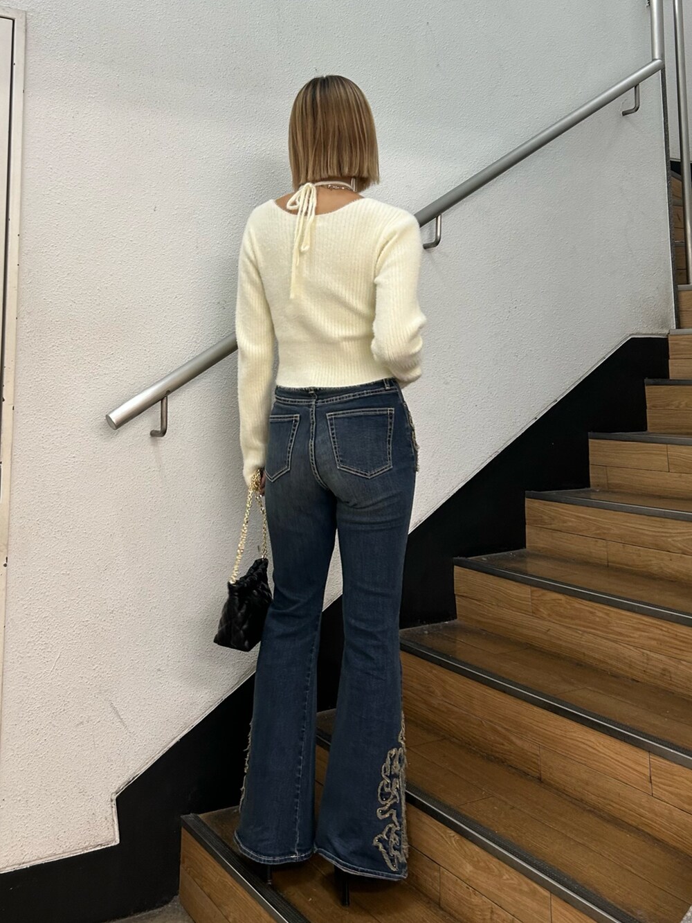 ホワイト系のニット/セーター、ブラック系のショルダーバッグ、ブルー系のデニムパンツを着用したレディースの秋コーディネートの3枚目の写真