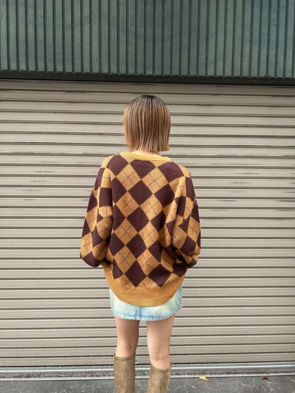 ブルー系のデニムスカート、ブラウン系のニット/セーター、ベージュ系のブーツを着用したレディースの秋コーディネートの5枚目の写真