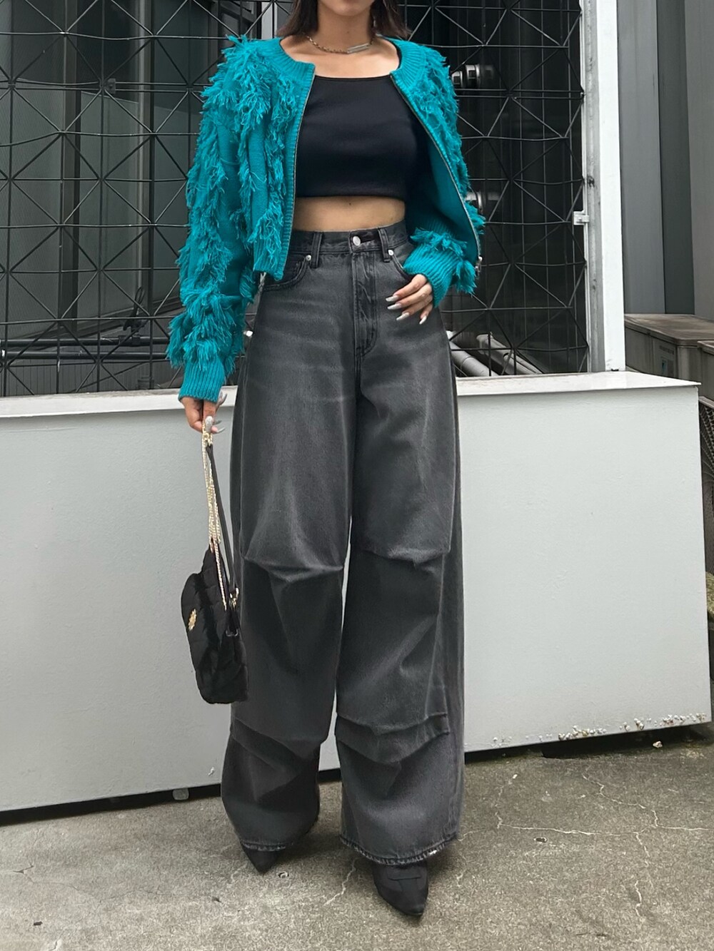 ブラック系のデニムパンツ、ブラック系のショルダーバッグ、ブルー系のニット/セーターを着用したレディースの夏コーディネートの2枚目の写真