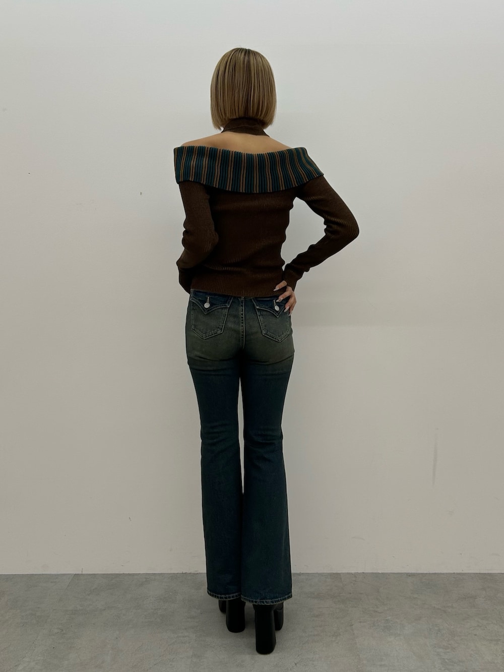 ブルー系のデニムパンツ、ブラウン系のニット/セーター、ブラック系のブーツを着用したレディースの夏コーディネートの2枚目の写真