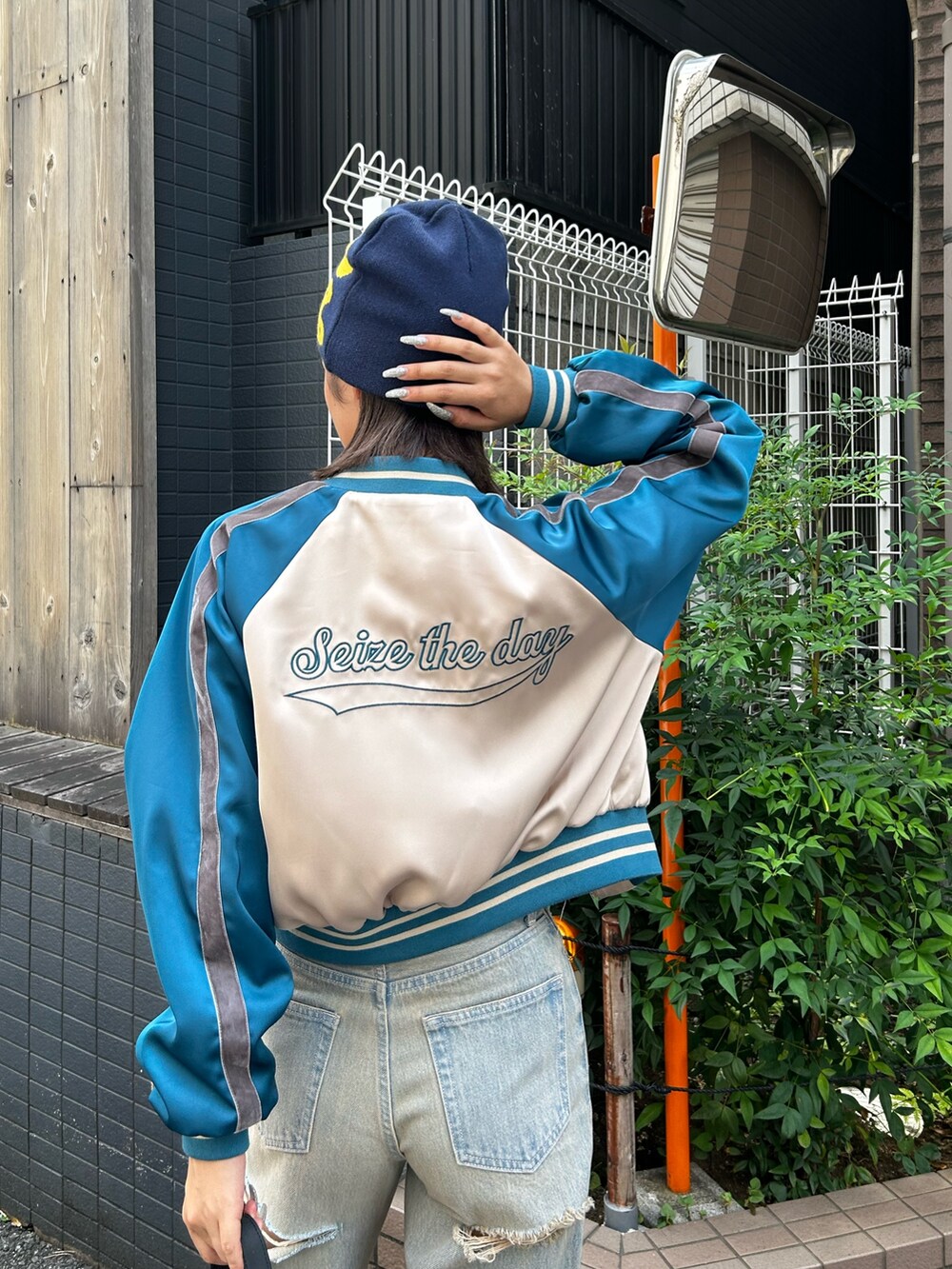 ブルー系のデニムパンツ、ベージュ系のブルゾン、ブラック系のブーツを着用したレディースの夏コーディネートの3枚目の写真