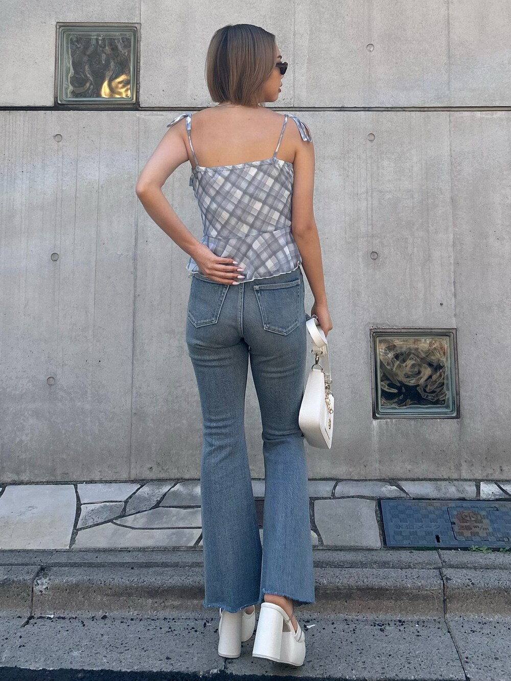 ブルー系のデニムパンツ、ブルー系のキャミソール、ホワイト系のショルダーバッグを着用したレディースの春コーディネートの2枚目の写真