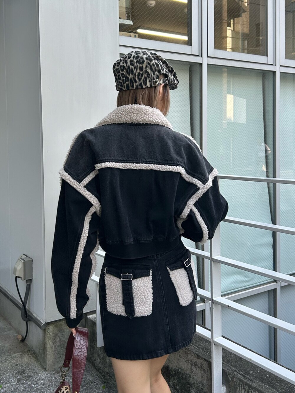 ブラック系のブルゾン、ブラック系のデニムスカート、ベージュ系のハンドバッグを着用したレディースの秋コーディネートの5枚目の写真