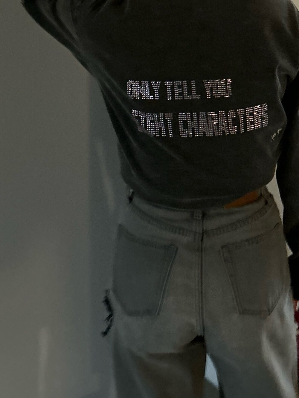 ブラック系のデニムパンツ、グレー系のTシャツ/カットソー、ブラック系のブーツを着用したレディースの冬コーディネートの3枚目の写真