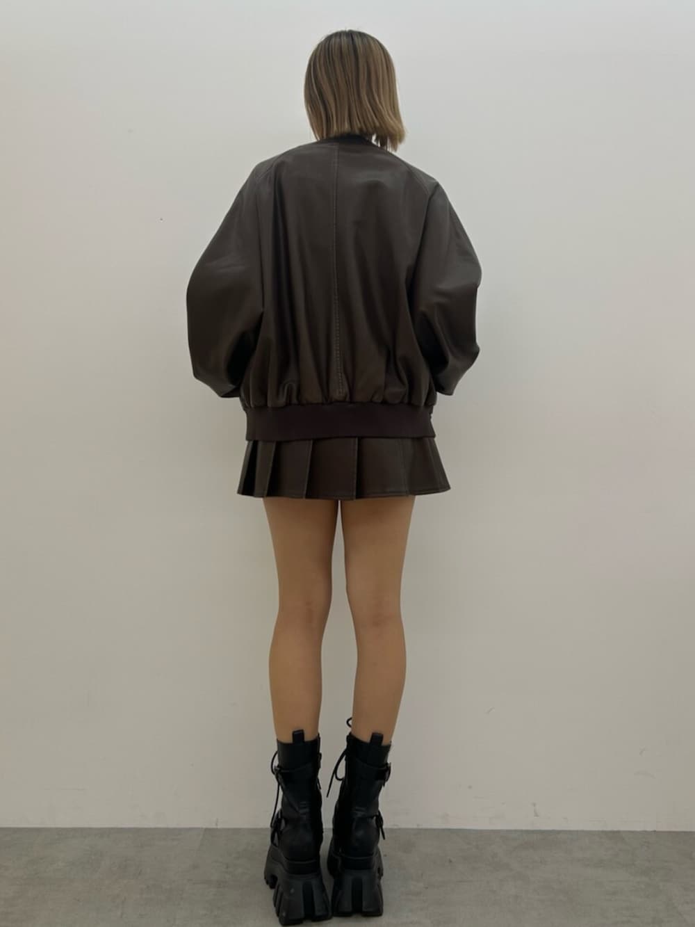 ブラック系のブーツ、ブラウン系のスカート、ブラウン系のブルゾンを着用したレディースの秋コーディネートの3枚目の写真