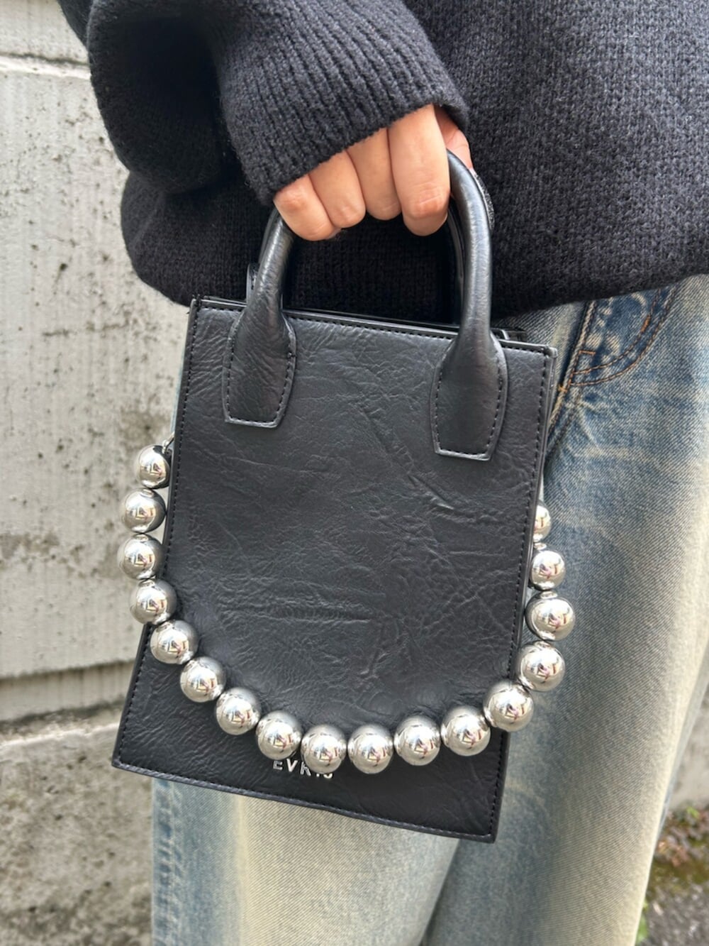 ブラック系のショルダーバッグ、ブラック系のニット/セーター、ブルー系のデニムパンツを着用したレディースの秋コーディネートの10枚目の写真