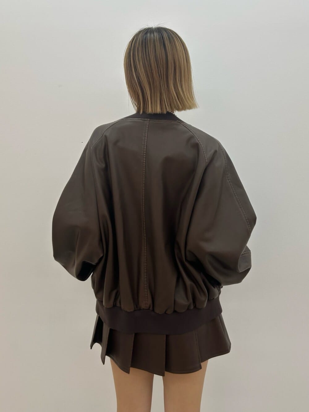 ブラック系のブーツ、ブラウン系のスカート、ブラウン系のブルゾンを着用したレディースの秋コーディネートの7枚目の写真