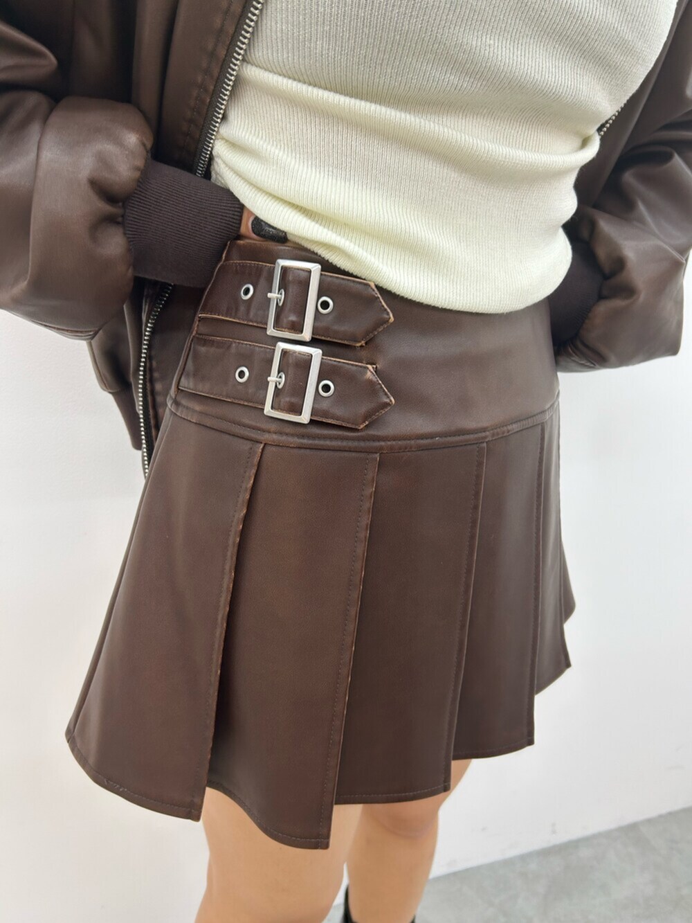 ブラック系のブーツ、ブラウン系のスカート、ブラウン系のブルゾンを着用したレディースの秋コーディネートの8枚目の写真