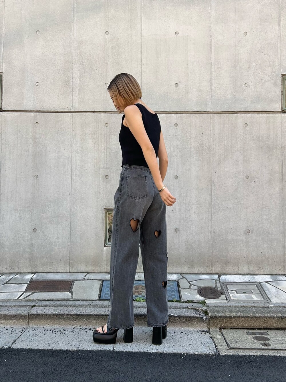 ブラック系のデニムパンツ、ブラック系のニット/セーター、ブラック系のサンダルを着用したレディースの春コーディネートの2枚目の写真