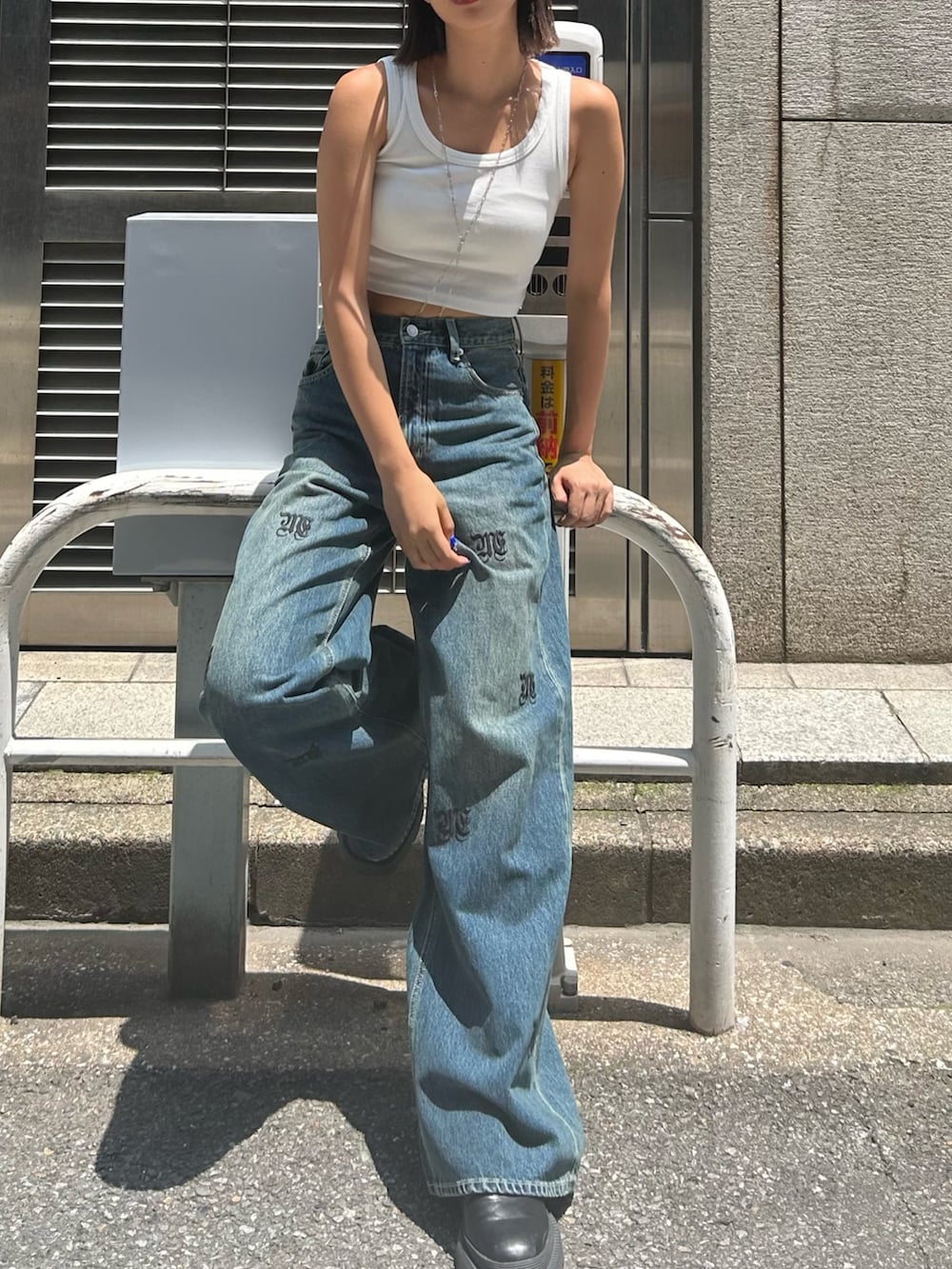 ブルー系のデニムパンツ、ホワイト系のタンクトップ、ブラック系のブーツを着用したレディースの春コーディネートの2枚目の写真