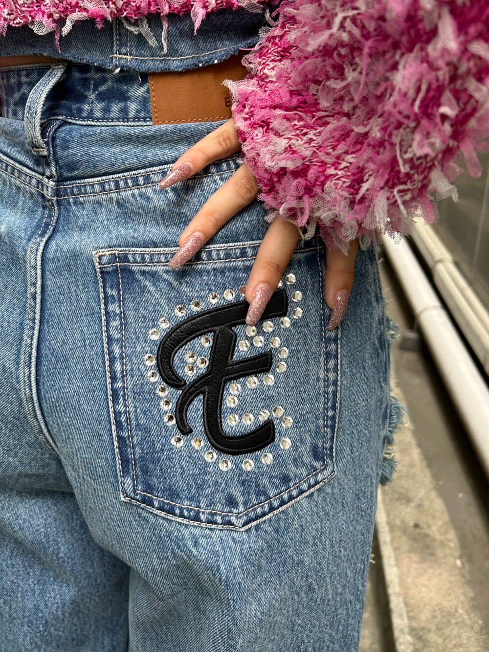 ブラック系のサンダル、ブルー系のデニムパンツ、ピンク系のニット/セーターを着用したレディースの夏コーディネートの3枚目の写真