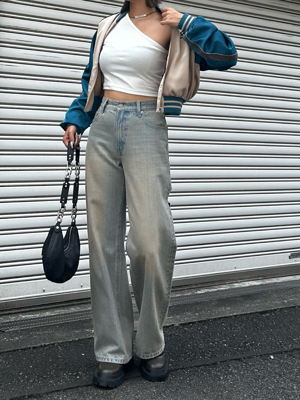 ブルー系のデニムパンツ、ベージュ系のブルゾン、ブラック系のブーツを着用したレディースの夏コーディネートの2枚目の写真