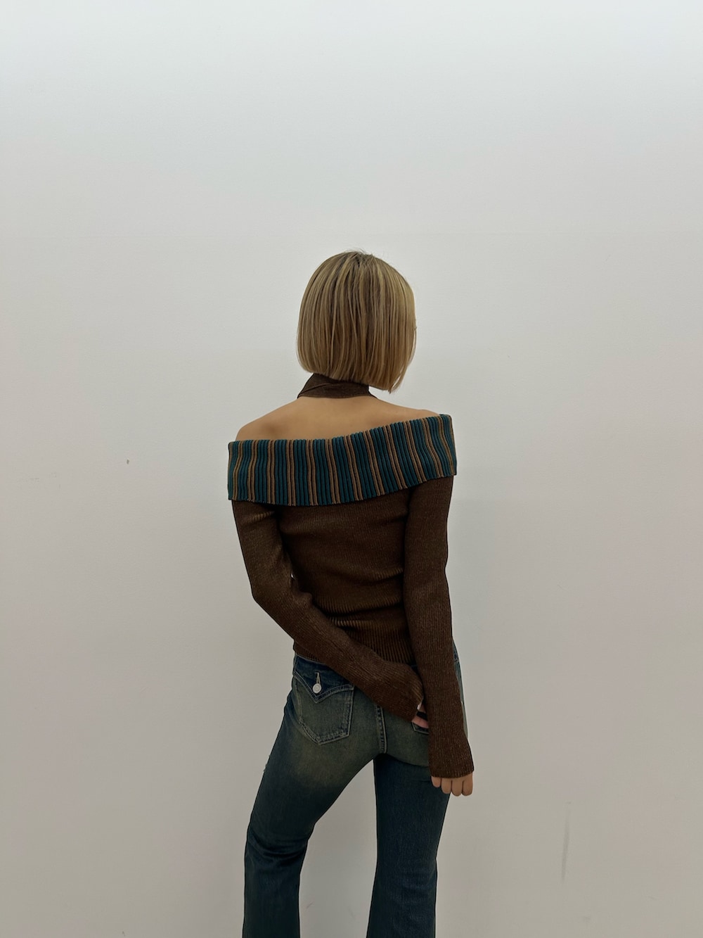 ブルー系のデニムパンツ、ブラウン系のニット/セーター、ブラック系のブーツを着用したレディースの夏コーディネートの3枚目の写真