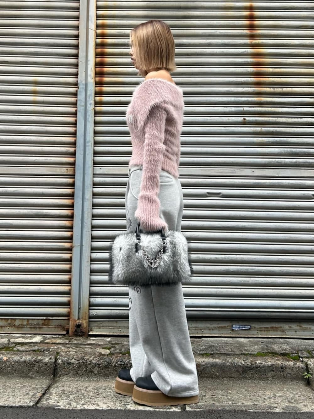 ブラック系のスリッポン、ピンク系のニット/セーター、グレー系のスウェットパンツを着用したレディースの秋コーディネートの2枚目の写真