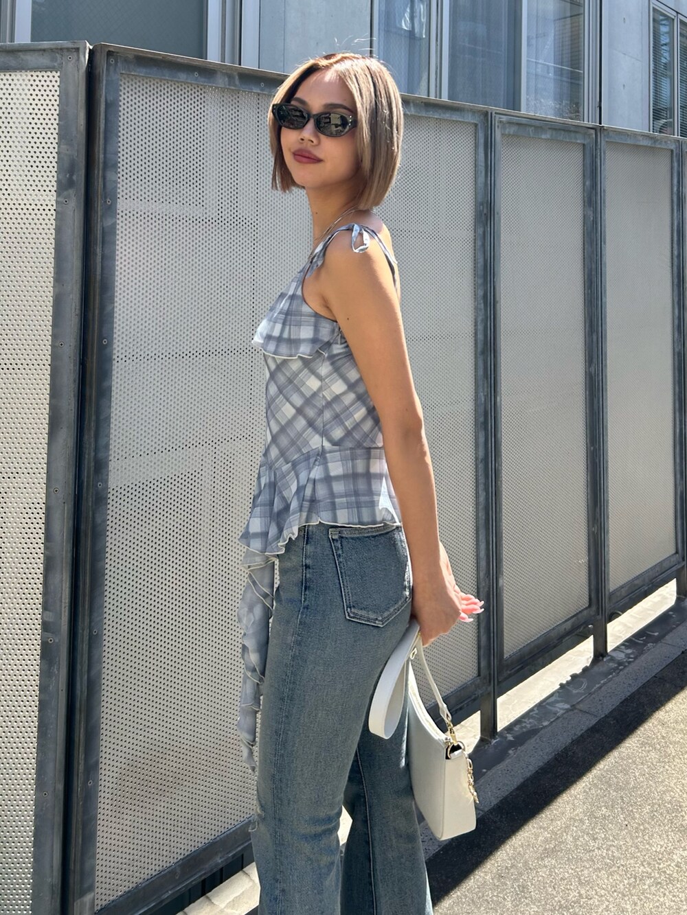 ブルー系のデニムパンツ、ブルー系のキャミソール、ホワイト系のショルダーバッグを着用したレディースの春コーディネートの3枚目の写真