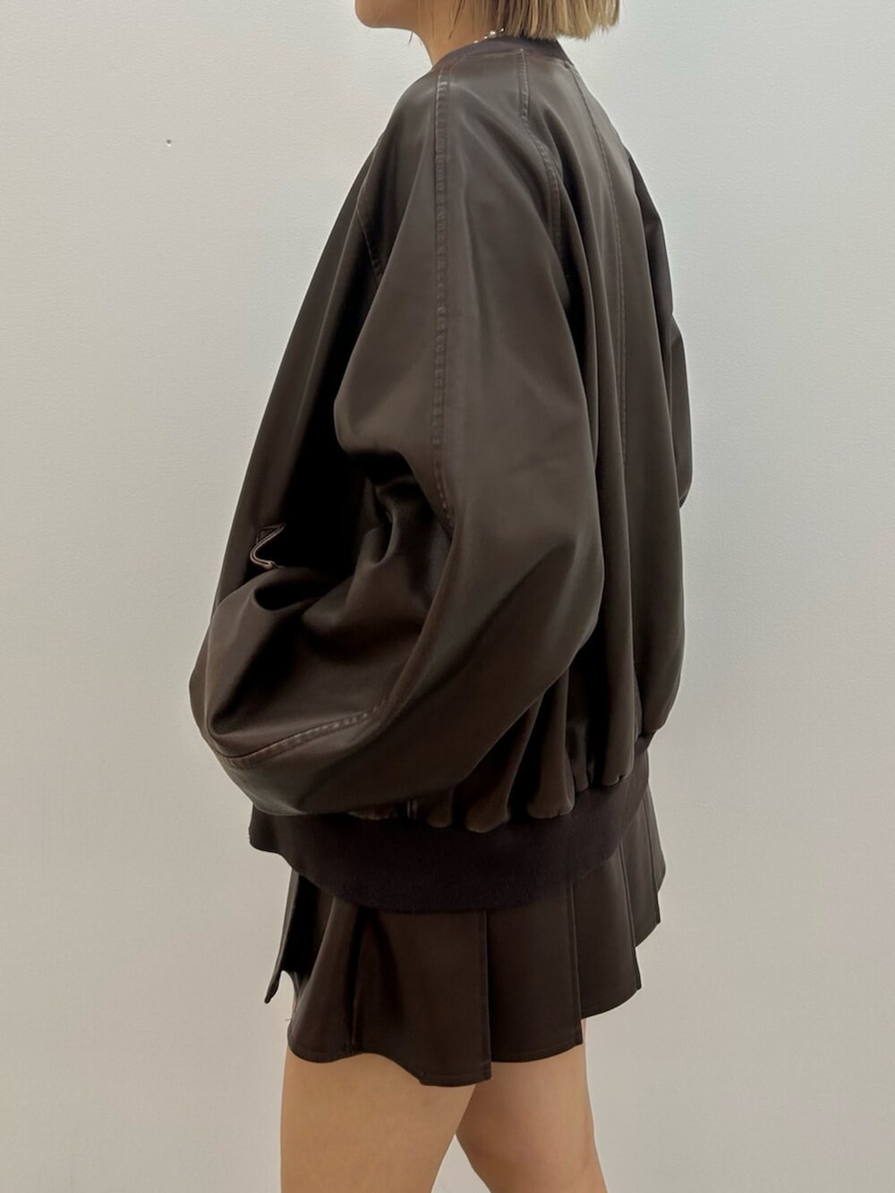 ブラック系のブーツ、ブラウン系のスカート、ブラウン系のブルゾンを着用したレディースの秋コーディネートの6枚目の写真