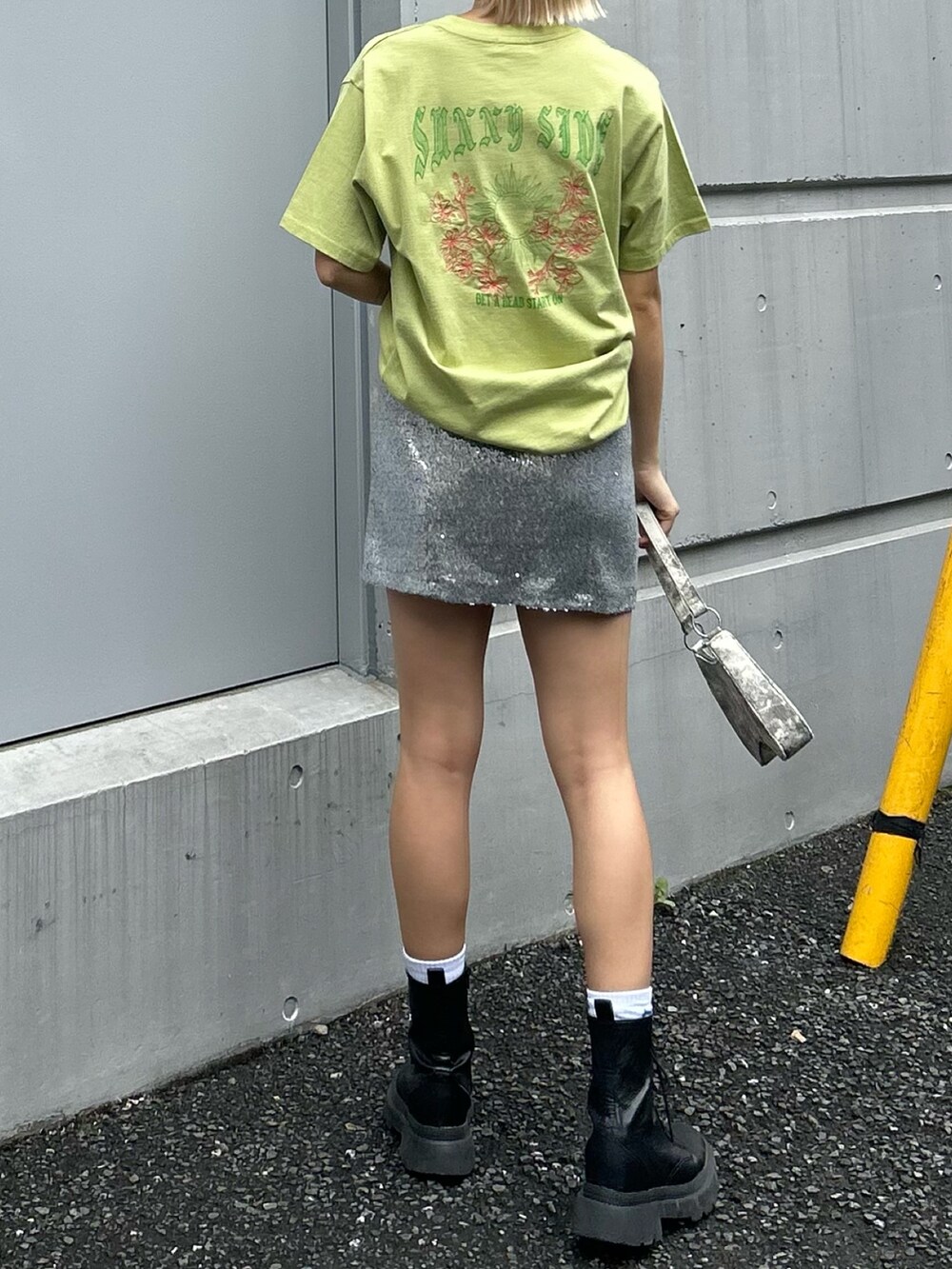 グリーン系のTシャツ/カットソー、シルバー系のスカート、ブラック系のブーツを着用したレディースの春コーディネートの2枚目の写真