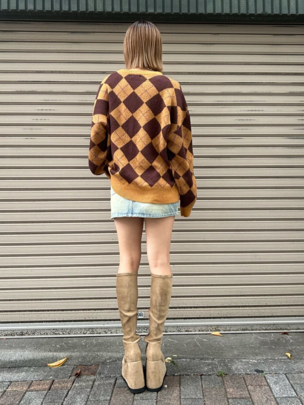 ブルー系のデニムスカート、ブラウン系のニット/セーター、ベージュ系のブーツを着用したレディースの秋コーディネートの3枚目の写真