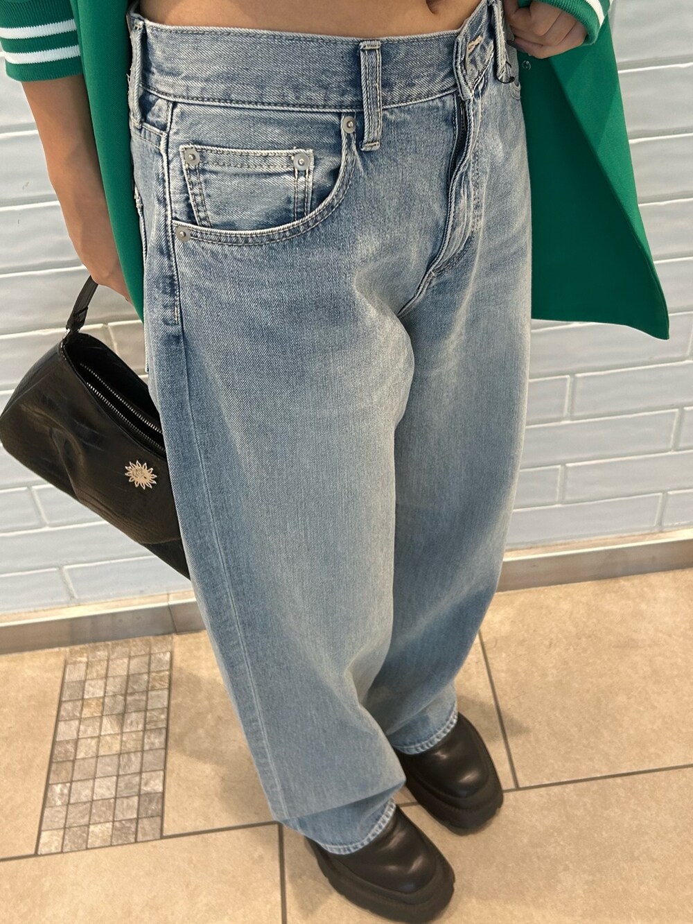 ブルー系のデニムパンツ、グリーン系のテーラードジャケット、ブラック系のハンドバッグを着用したレディースの秋コーディネートの3枚目の写真