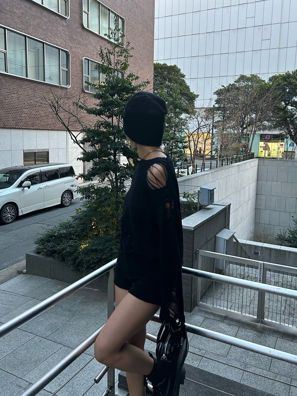 ブラック系のショルダーバッグ、ブラック系のニット/セーター、ブラック系のブーツを着用したレディースの春コーディネートの3枚目の写真