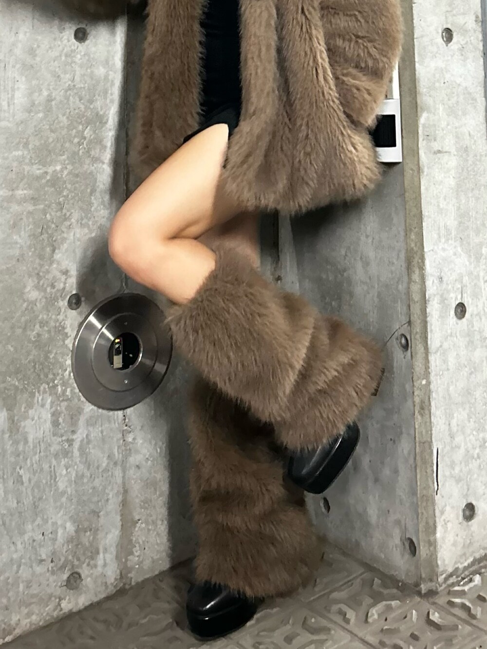 ブラウン系のブルゾン、ブラック系のブーツ、ブラウン系のレッグウォーマーを着用したレディースの秋コーディネートの4枚目の写真