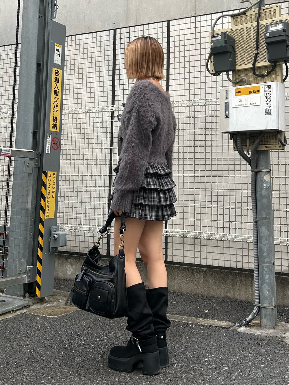 グレー系のニット/セーター、ブラック系のスカート、ブラック系のハンドバッグを着用したレディースの秋コーディネートの3枚目の写真