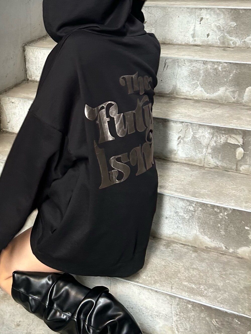 ブラック系のパーカー、ブラック系のブーツ、シルバー系のショルダーバッグを着用したレディースの冬コーディネートの2枚目の写真