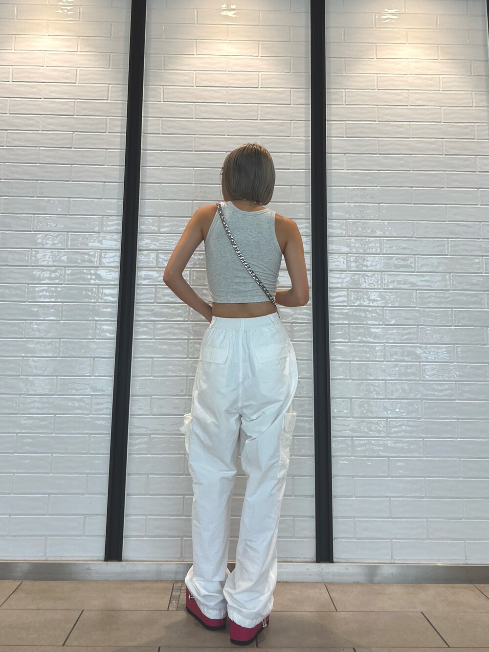 ホワイト系のカーゴパンツ、シルバー系のショルダーバッグ、グレー系のタンクトップを着用したレディースの夏コーディネートの2枚目の写真