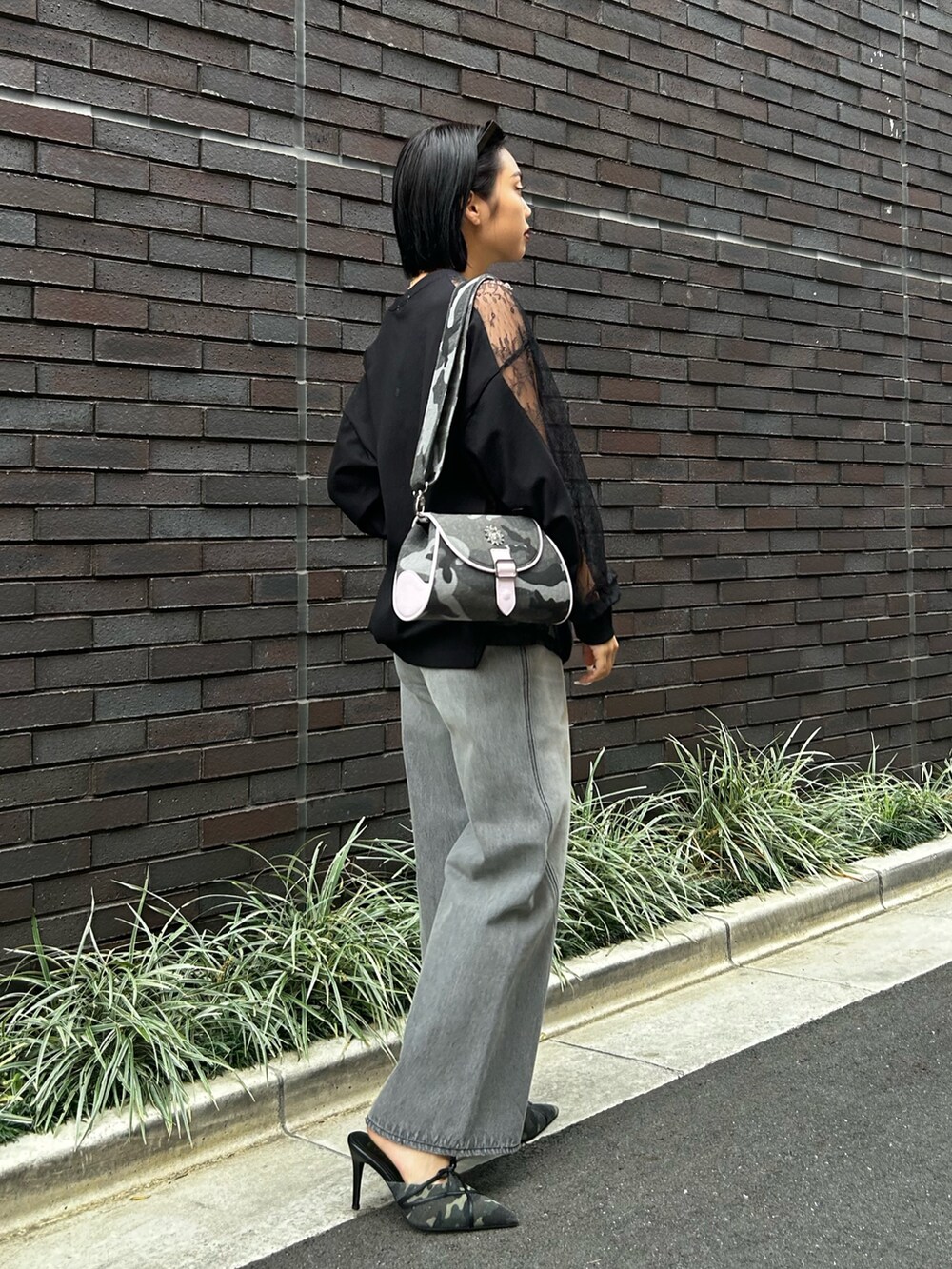 ブラック系のデニムパンツ、ブラック系のTシャツ/カットソー、グリーン系のサンダルを着用したレディースの冬コーディネートの2枚目の写真