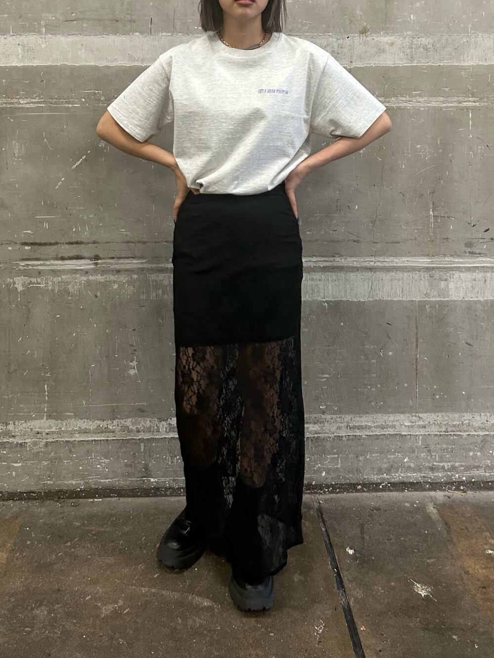 ブラック系のスカート、グレー系のTシャツ/カットソー、ブラック系のブーツを着用したレディースの春コーディネートの2枚目の写真