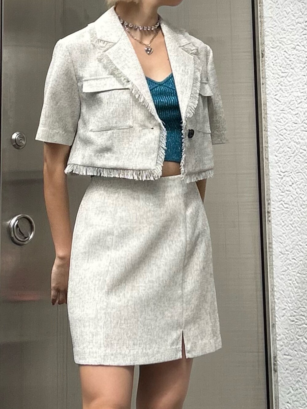 ホワイト系のスカート、ホワイト系のテーラードジャケット、ブルー系のキャミソールを着用したレディースの春コーディネートの2枚目の写真