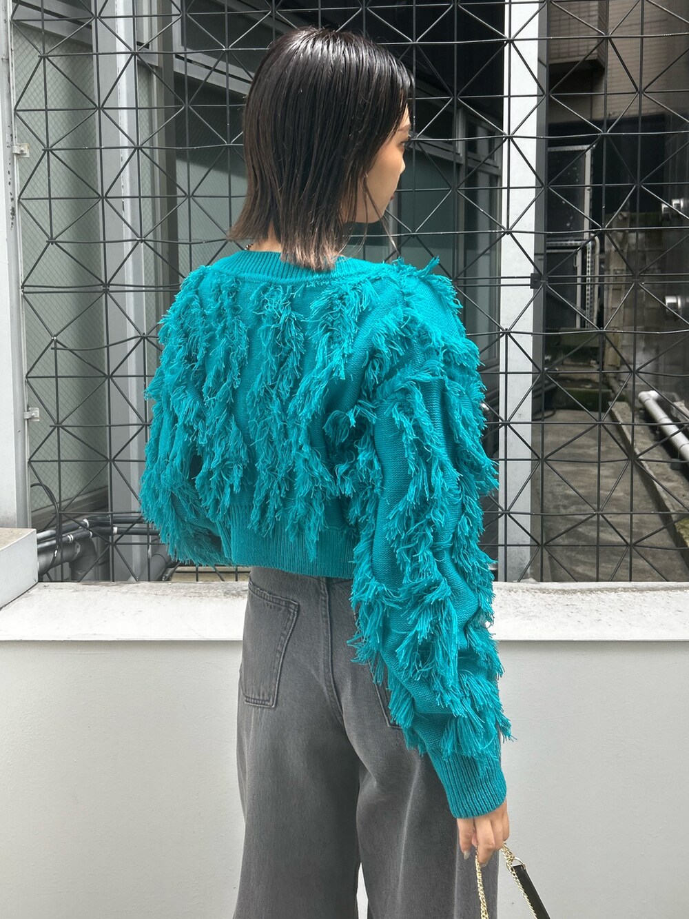 ブラック系のデニムパンツ、ブラック系のショルダーバッグ、ブルー系のニット/セーターを着用したレディースの夏コーディネートの3枚目の写真