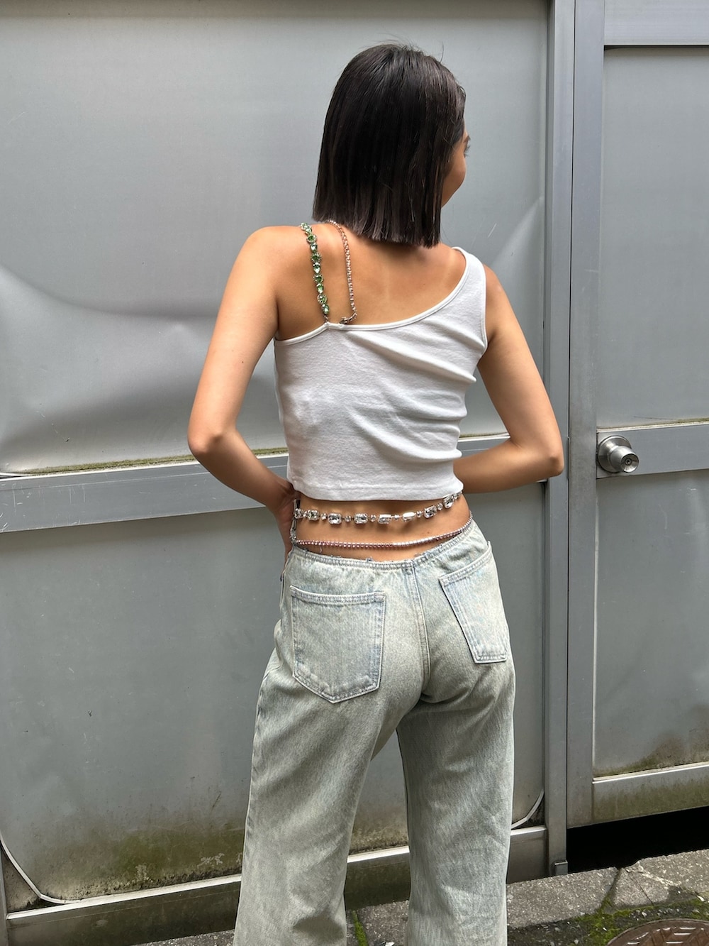 ブルー系のデニムパンツ、ホワイト系のタンクトップ、ホワイト系のサンダルを着用したレディースの春コーディネートの2枚目の写真