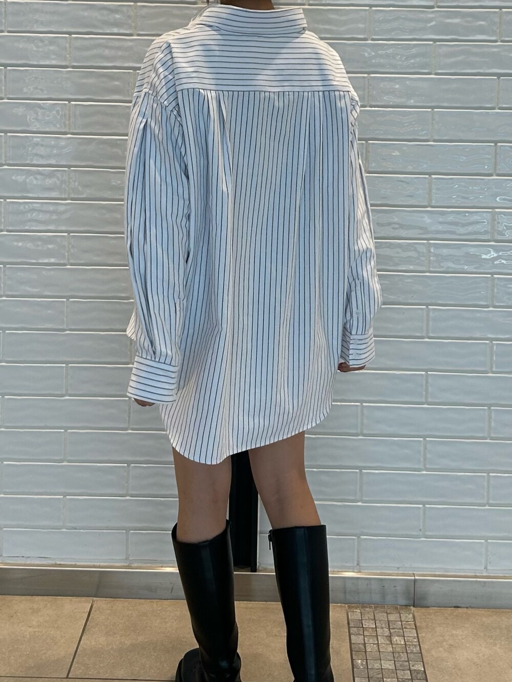 ホワイト系のシャツ/ブラウス、ブルー系のショルダーバッグ、ブラック系のブーツを着用したレディースの冬コーディネートの2枚目の写真